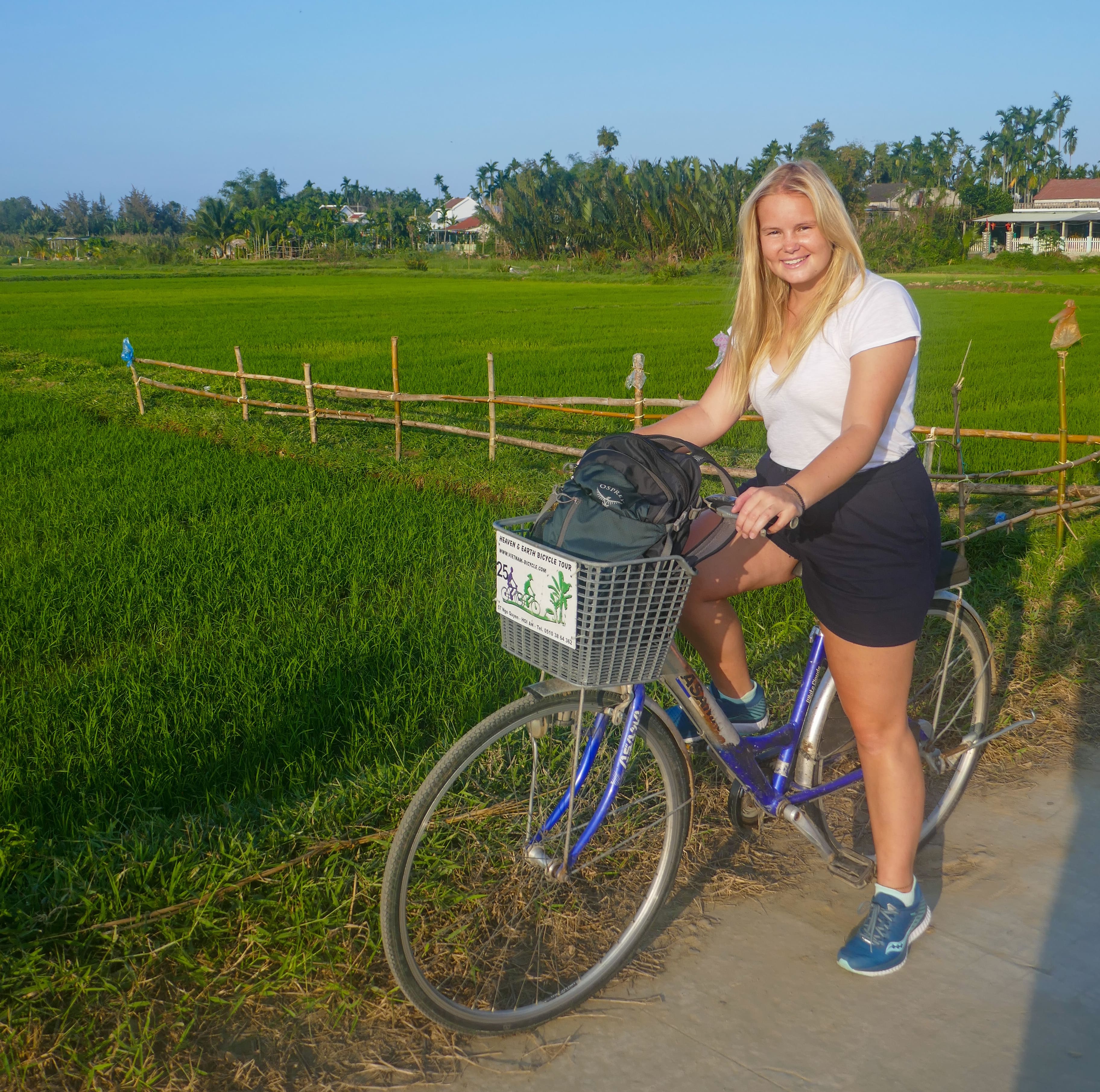 woman on bicycle in green rice paddies smiling